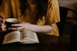 woman holding mug in front of book