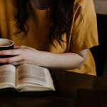 woman holding mug in front of book