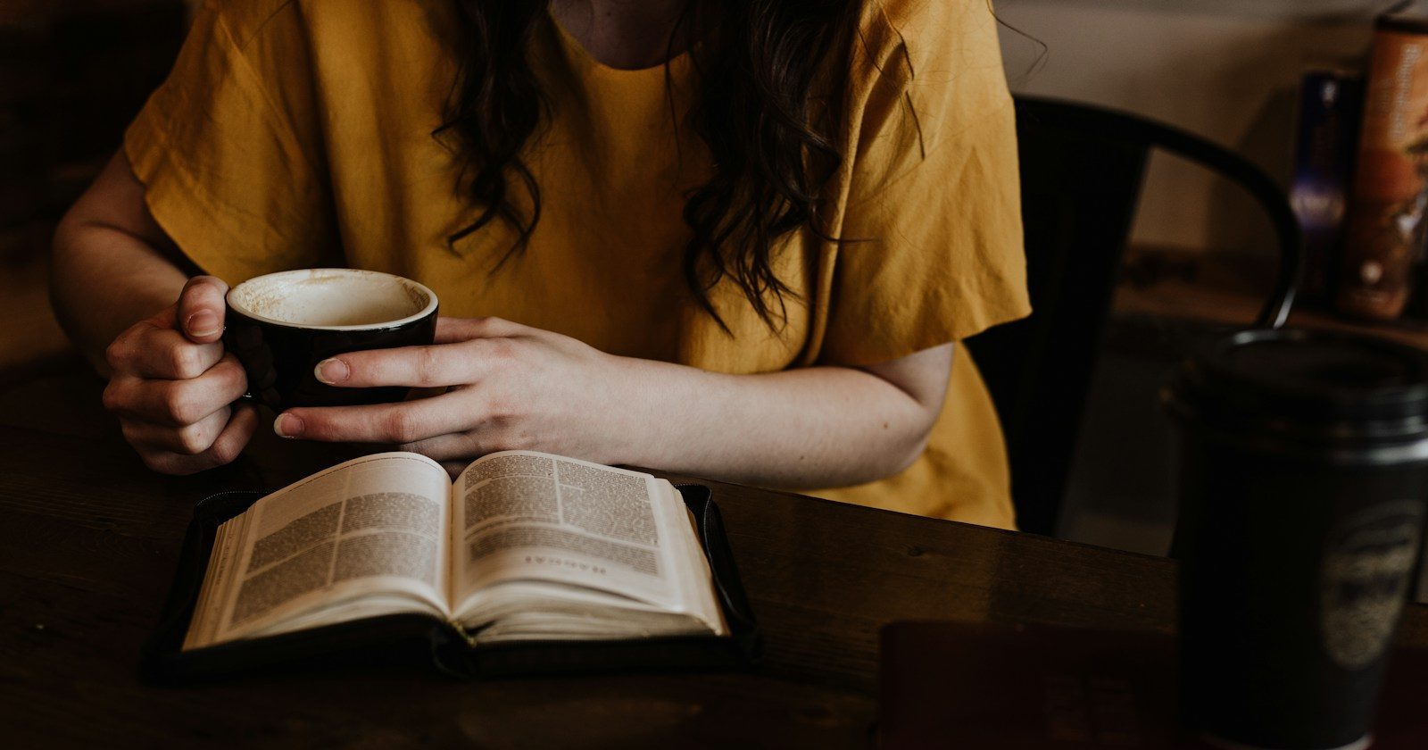 woman holding mug in front of book